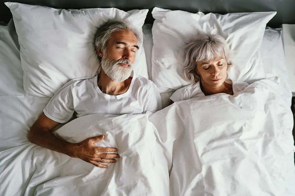 Schlafendes Ehepaar in weißer Bettwäsche