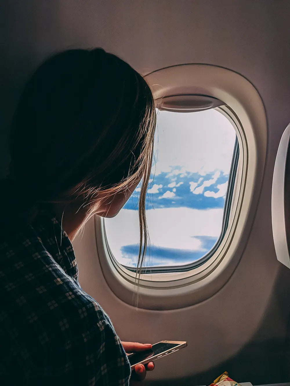Frau schaut aus Flugzeugfenster